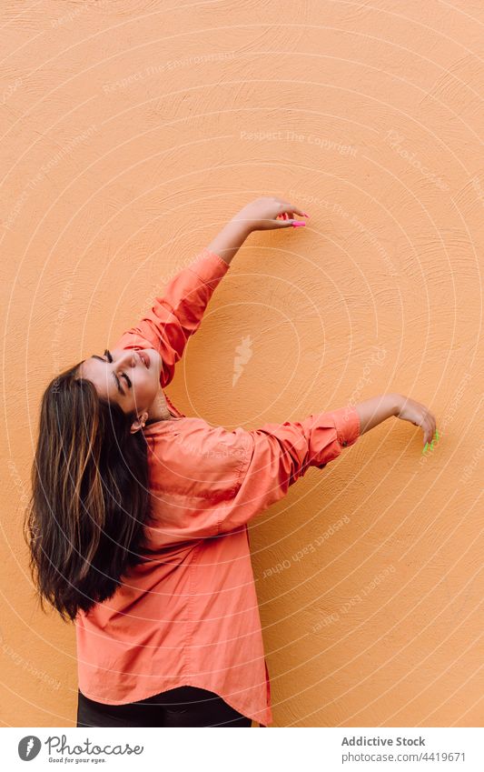 Stylish woman dancing with raised hands style carefree cool dance tranquil individuality appearance feminine female serene move arms raised delicate posture