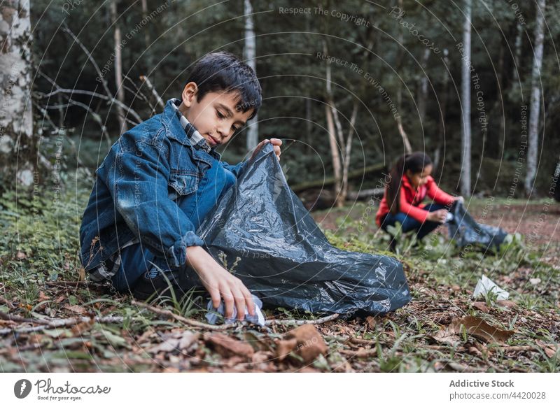 Ethnic children collecting garbage from land in forest volunteer protect environment nature conserve preserve plastic pick rubbish bottle trash junk inorganic