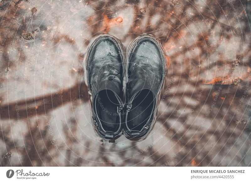 Boots over puddle top view child fun splashing rain wet playful boot person dirt mud rubber young jump happy jumping joy funny leg pool run messy kid one person