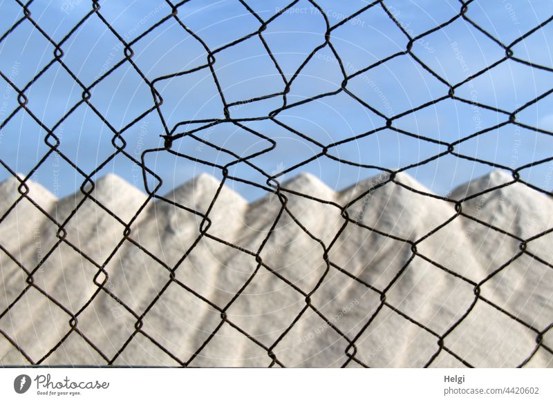 Salt mountains in a salt extraction plant behind the fence Salt crystals Drying piled up storage sea salt Ses Salines Majorca Deserted Colour photo Saltworks