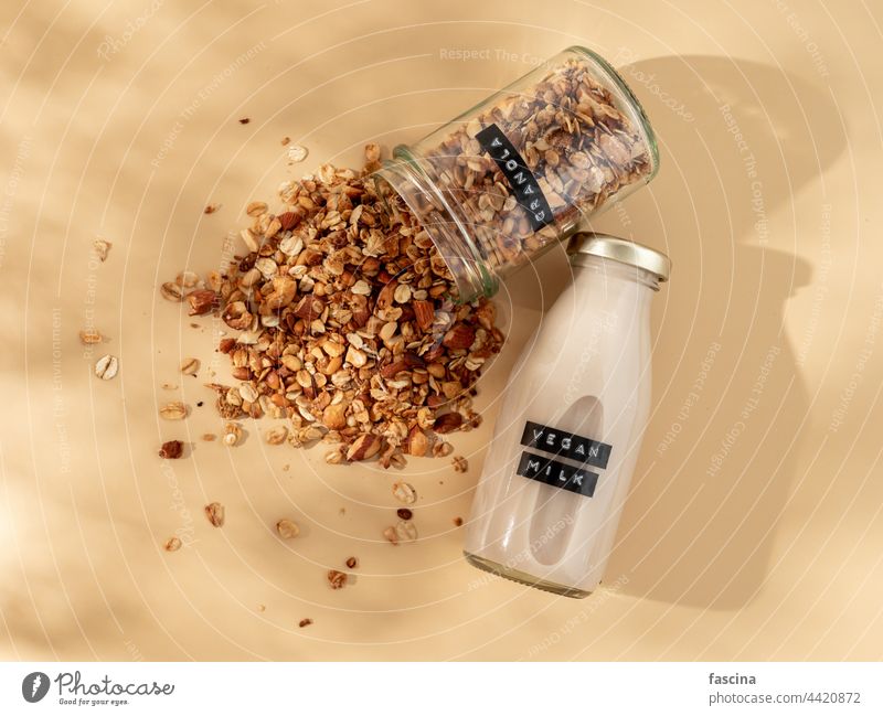 Granola and vegan milk on yellow bg. Top view granola non-dairy dairy-free aesthetic breakfast muesli jar pastel oatmeal beige copy space flatlay authentic