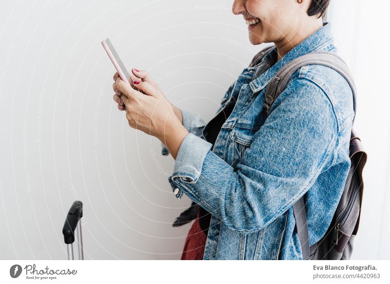 close up of happy caucasian woman at train station using smart phone app while waiting. Travel concept unrecognizable mobile phone travel technology baggage