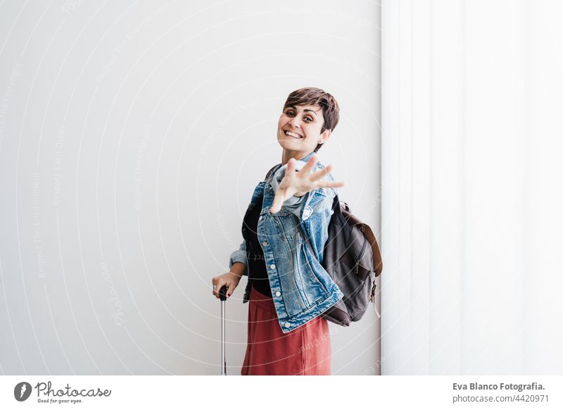 happy backpacker caucasian woman at train station waiting to catch train. Travel concept travel public transport young suitcase luggage baggage smiling daytime