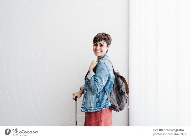 smiling backpacker caucasian woman at train station waiting to catch train. Travel concept travel public transport young suitcase luggage baggage happy daytime