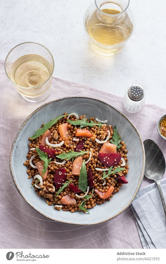 Closeup of a salmon and lentil salad seen from above top view food top view table table cloth wine bottle wine glass mustard plum smoked salmon salad arugula