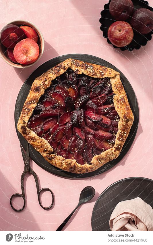 Closeup of a plum cake seen from above plate bakery knife pastries plums cooking close up sweet pastries no people tart - dessert fruit tart pink background