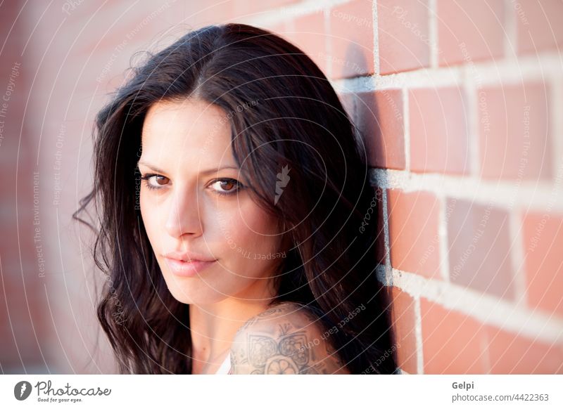 Beautiful brunette with red brick wall of background young sunny girl beautiful hair summer people beauty portrait natural fashion female sunshine yellow