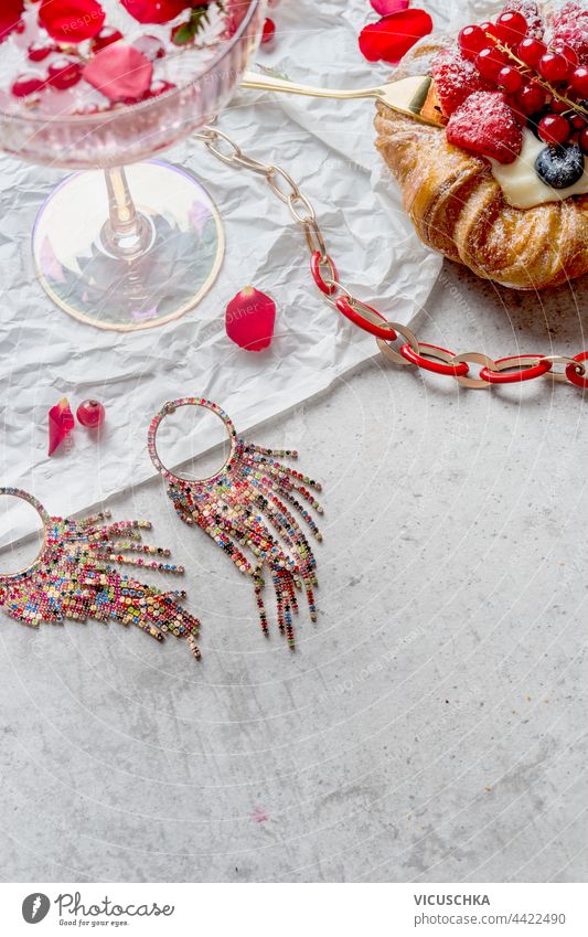 Glamorous cocktail glass with champagne and red fruits on desk with cake and jewelry. Top view. glamorous top view sweet wine table elegance background drink