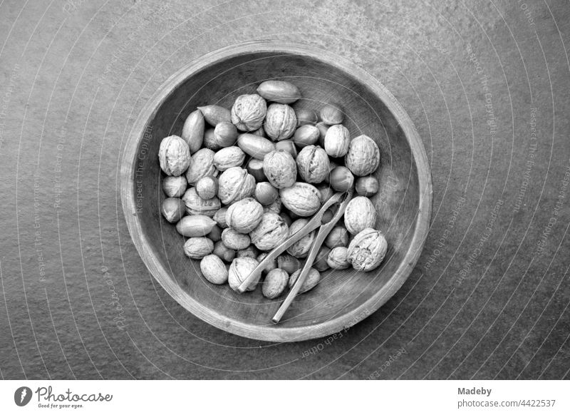 Beautiful round wooden bowl with walnuts and hazelnuts at Advent time in a designer apartment on a farm in Rudersau near Rottenbuch in the district of Weilheim-Schongau in Upper Bavaria, photographed in traditional black and white