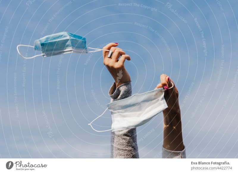 unrecognizable two woman hands holding face mask during pandemic corona virus outdoors over blue sky. Breathing and freedom concept women young caucasian female