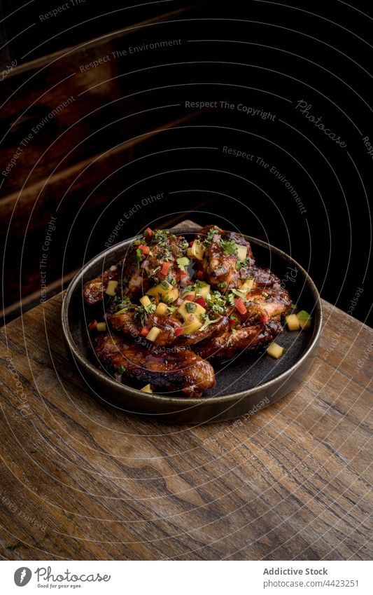 Grilled chicken wing in BBQ sauce with vegetables on round plate food fast food bbq tasty portion barbecue appetizing dish meal roast restaurant delicious serve