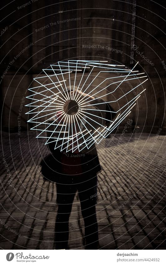 Pane art with a difference.  The shop window pane shows cracks. In the evening light the photographer stands with bag on the paved street in front of the cracked window.