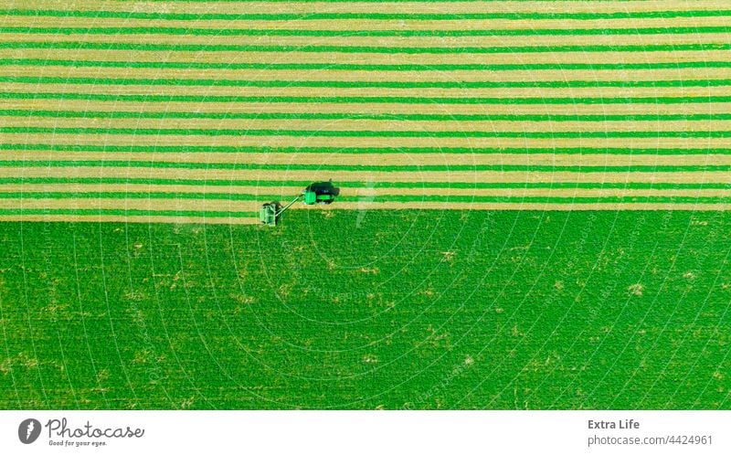 Aerial view of tractor as tow lawn mower machinery behind Above Agriculture Alfalfa Attached Clipper Clover Crop Cut Cutter Drag Farming Farmland Fast Field