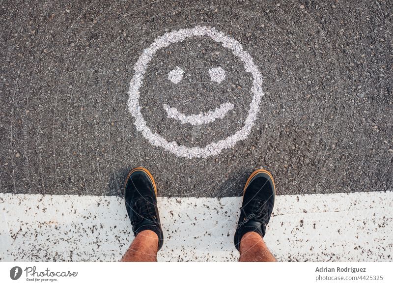 Person stands in front of a smile emoticon.  Concept for World Smile Day smiles Smiley face smile,expression Smile picture smile,expression,people smiled