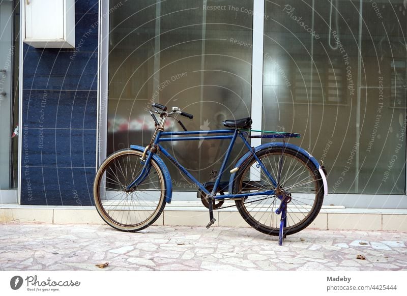 Old blue bicycle in front of blue house entrance with a lot of glass in Adapazari in the province of Sakarya in Turkey Wheel Bicycle man's bicycle touring bike