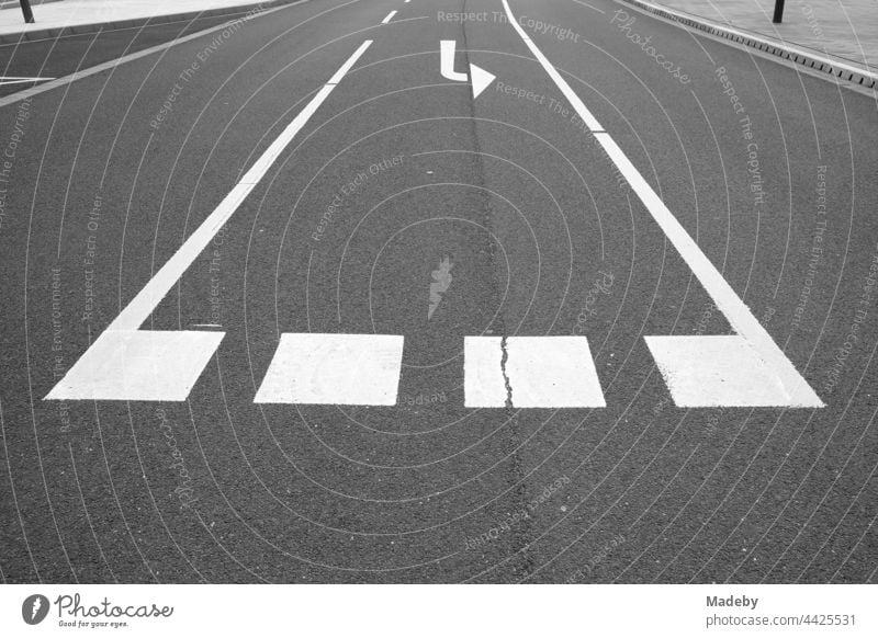 White lane marking of a left-turn lane on grey asphalt at Leitz-Park in Wetzlar on the Lahn in Hesse, photographed in classic black and white Traffic lane