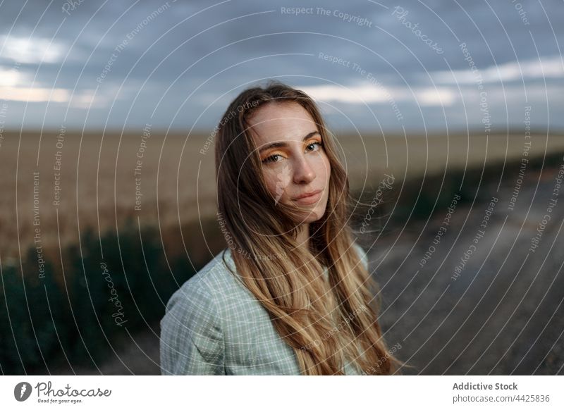 Stylish model in field under cloudy sky mindfulness style nature woman countryside dreamy concentrate atmosphere meadow vegetate grow reflective cereal