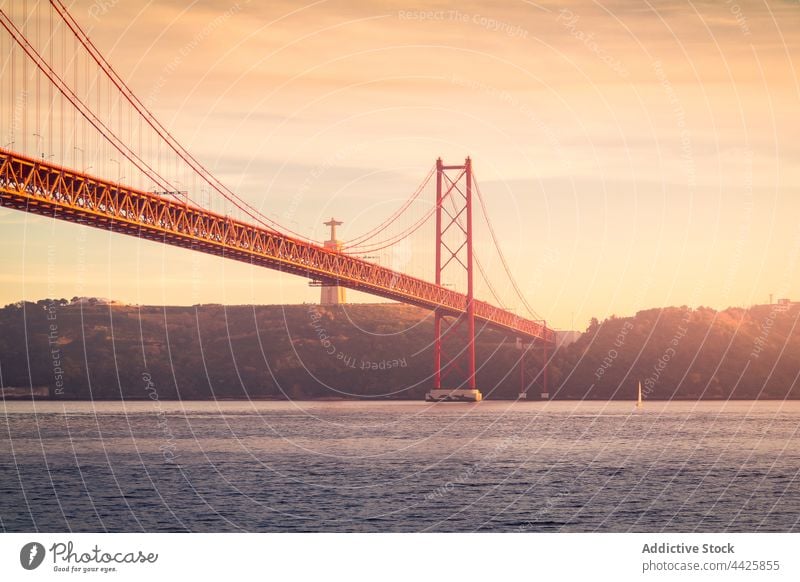 Modern bridge over river at sunset shore sky cloudy evening modern connect monument lisbon portugal almada 25 de abril bridge sanctuary of christ the king