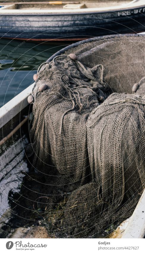 an old fishing net lies in a small fishing boat Fishing net Gray Brown Fishing boat Exterior shot Fishery Net Reticular Ocean Day Fishing port Fishing village