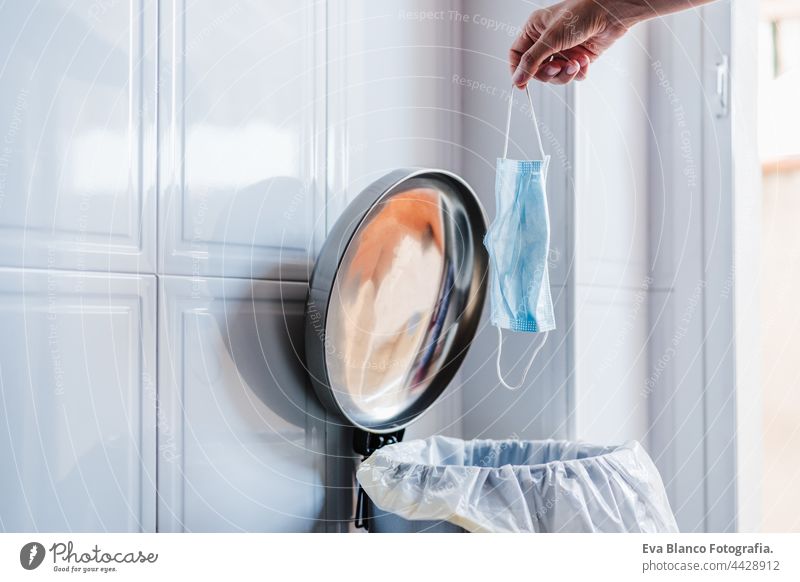 vertical view of unrecognizable woman hand throwing protective mask into waste at home. Corona virus and recycle concept face mask daytime recycling