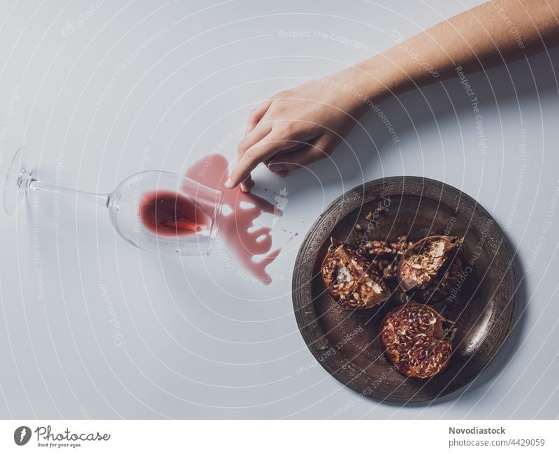 One arm, a plate with pomegranates and a wine of glass spilled on a table Hand Fingers Woman Human being Plate Colour photo Interior shot Arm Pomegranate Shadow