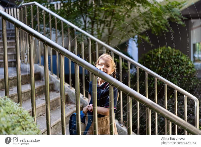 Schoolgirl back to school after summer vacations. Child in uniform standing early morning outdoor. backpack education public school schoolchild student pupil