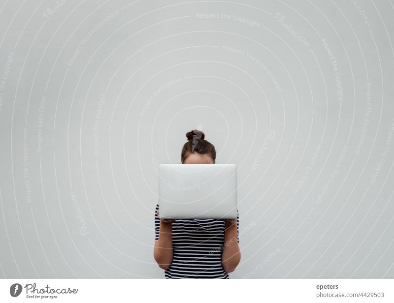 Young woman in jeans and t-shirt holds a silver laptop in front of her face brown hair Computer Self-confident Copy Space hide behind a computer Participation