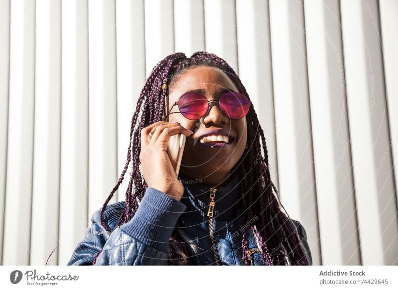 Black woman with braids having a phone call on smartphone using afro style cheerful toothy smile urban trendy gadget african american black ethnic female mobile