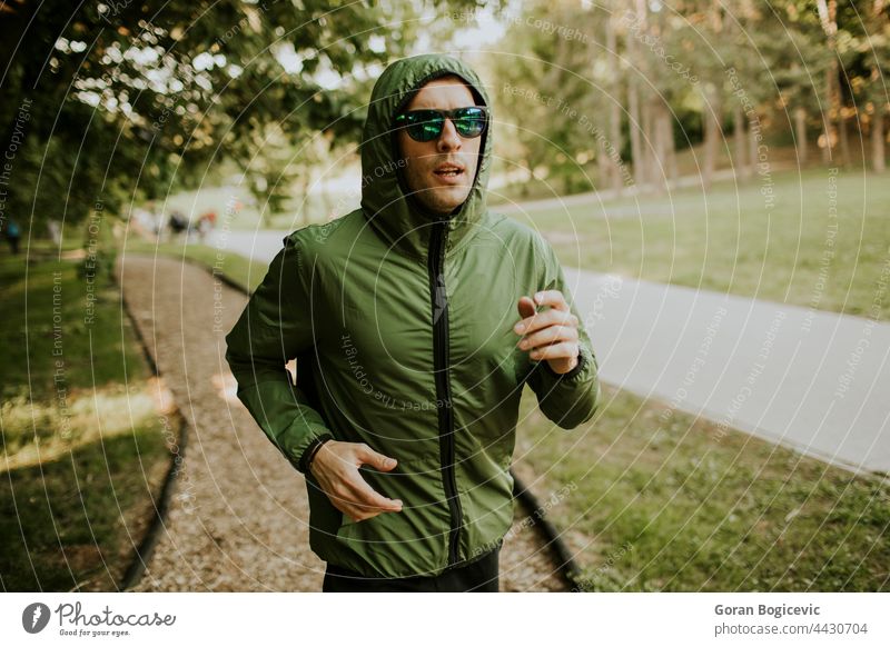 Athletic young man running while doing workout in sunny green park action active activity adult athlete athletic caucasian endurance exercise fit fitness grass