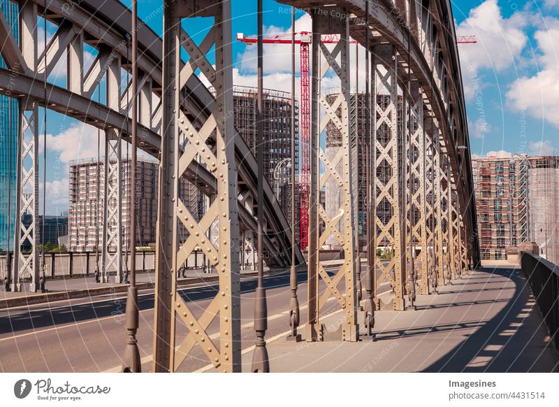 Arch bridge Honsellbrücke and Frankfurt city center Ostend. Luxury apartments under construction with crane. Skyscraper building on construction site. Frankfurt am Main, Germany