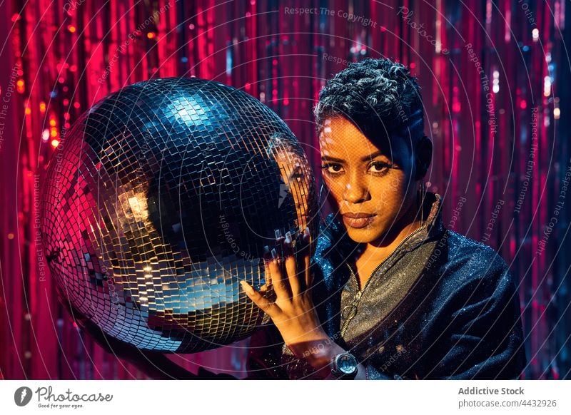 Stylish black model with makeup holding on disco ball individuality stylish gaze woman nightclub portrait style haircut african american ethnic glitter ball