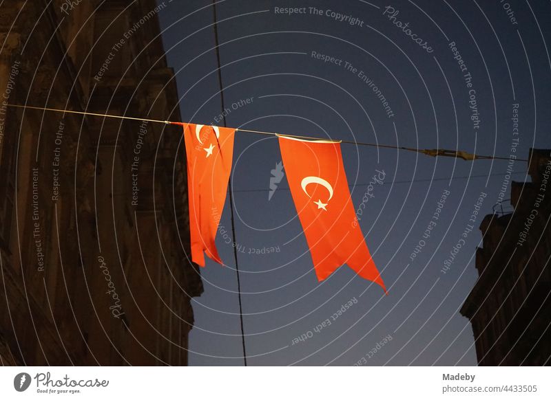 Red Turkish flags at night in the light of the street lights at the Galata quarter in the Istiklal Caddesi in the Beyoglu district of Istanbul on the Bosporus in Turkey