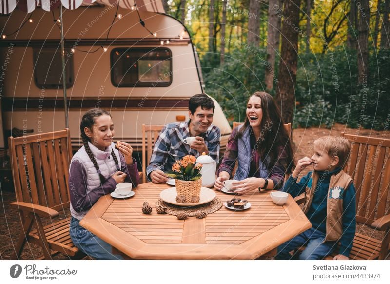 Happy family on a camping trip relaxing in the autumn forest. Camper trailer. Fall season outdoors trip fall nature father mother together fun happy people park