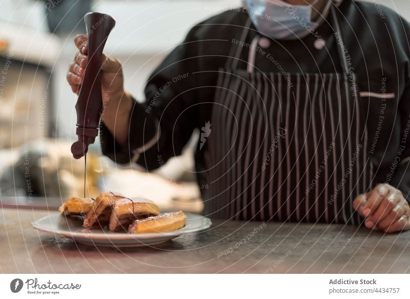 Crop anonymous chef decorating Belgian waffles with chocolate sauce decorate dessert treat man sweet prepare kitchen cook bottle baked berry ripe delicious