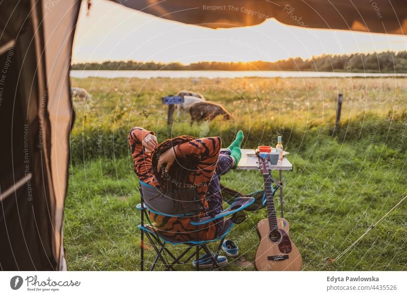 Woman relaxing in front of the tent during sunset campsite camping meadow grass field rural green countryside adventure hiking Wilderness wild vacation travel