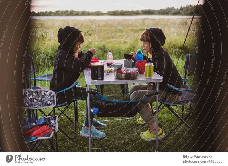 Children eating in front of the tent at a campsite children family kids food camping meadow grass field rural green countryside adventure hiking Wilderness