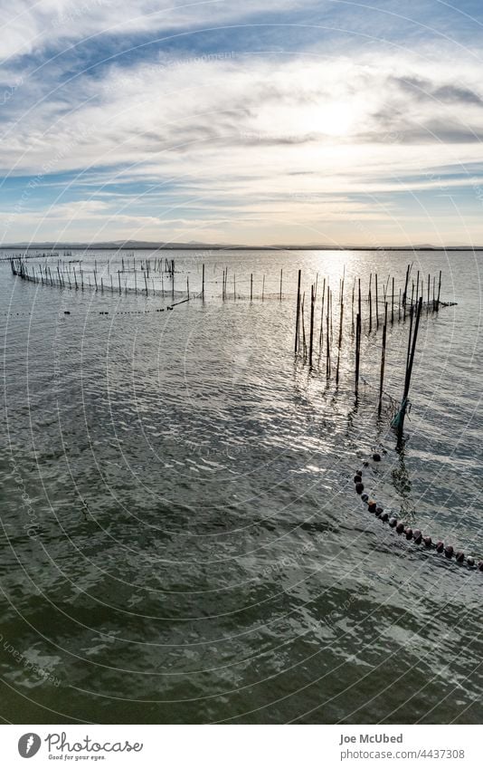 Sunset over the jetty with cloudy skies sky sunset background bay beach calm coast cumulus dawn dramatic dusk evening fishing nets horizon landscape nature