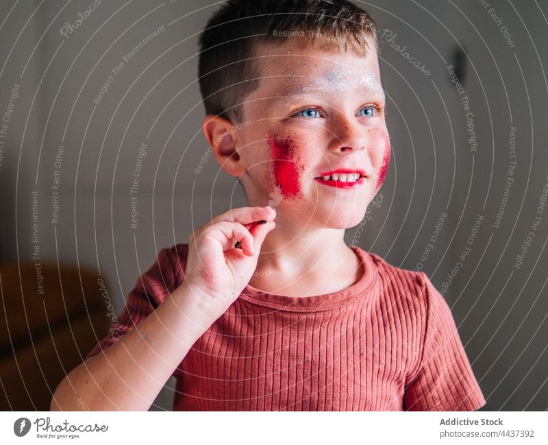 Dirty boy with makeup on cheeks at home messy cosmetic beauty dirty focus childhood red lips house decorative attentive spare time weekend concentrate color