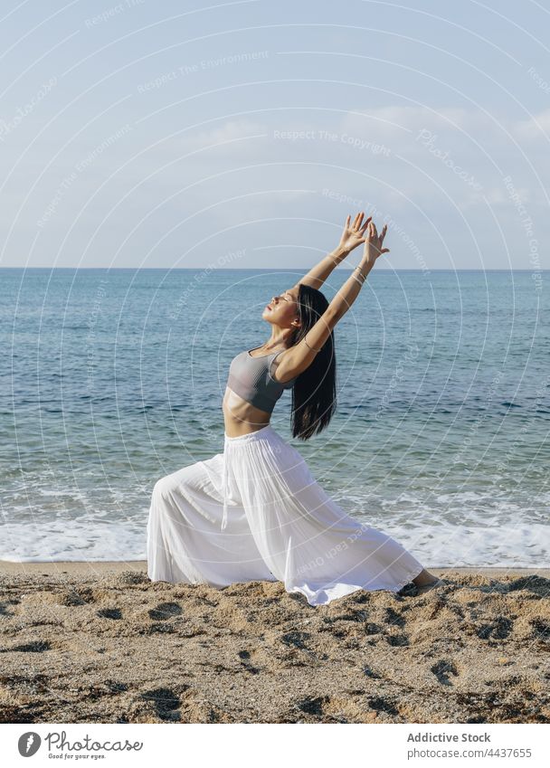 Asian woman doing Crescent Lunge pose on sea beach crescent lunge balance yoga energy vitality healthy lifestyle wellness seashore practice wellbeing ocean