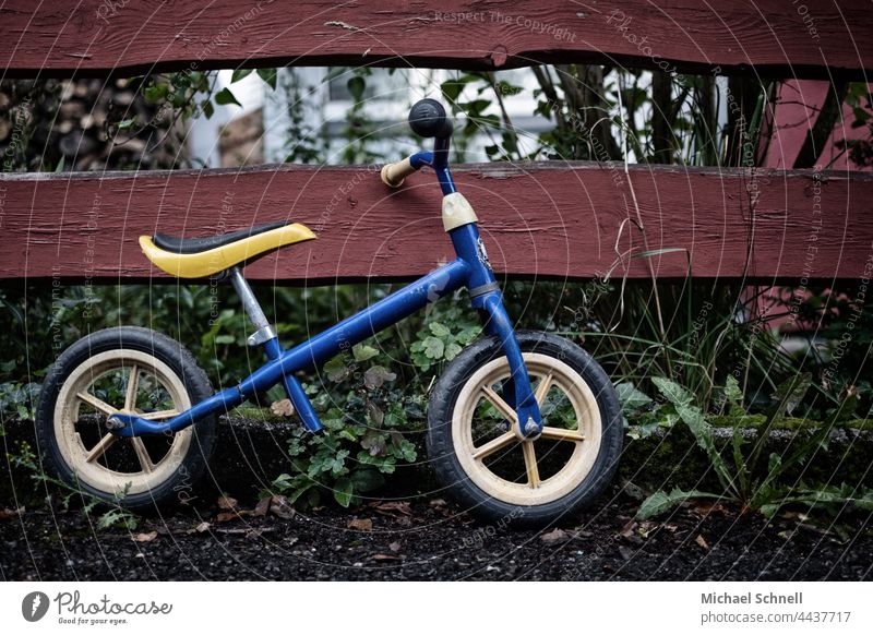 Old wheel on the fence impeller Child Infancy Exterior shot Movement Toddler Bicycle Playing Former Past Review Longing melancholically melancholy Meditative