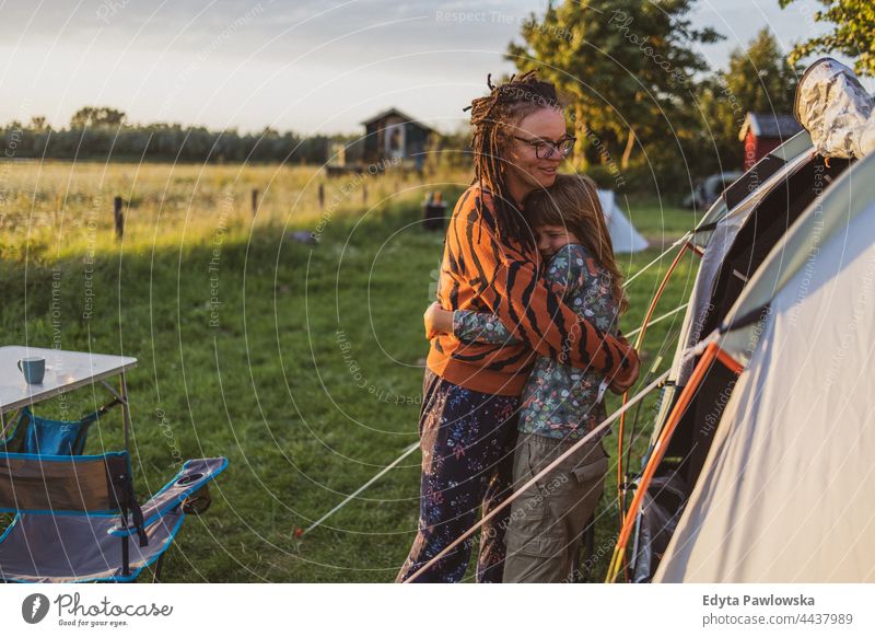 Mother and daughter hugging in front of the tent at the campsite mother parent together love fun joy children family kids camping bike cycling meadow grass