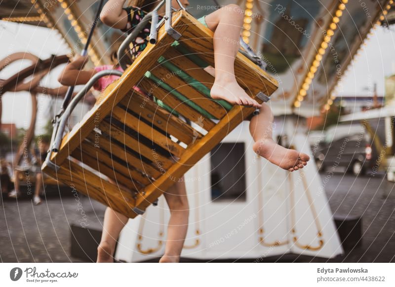 Children having fun on carousel ride feet foot bare feet merry-go-round riding swings fairground funny together amusement park vacation adventure summertime day