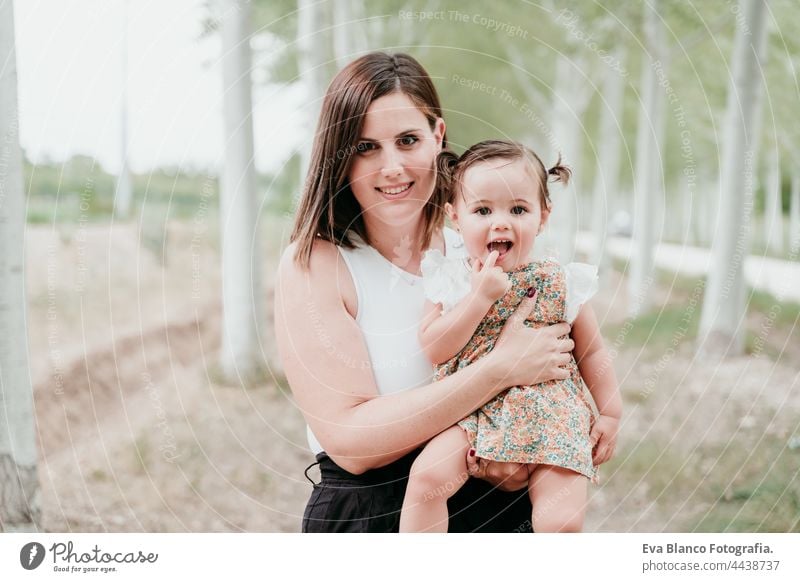 portrait of beautiful mother holding baby girl in trees path. Family, fun and nature concept forest happy childhood smiling run caucasian Spain dress innocent