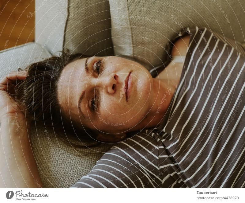 Portrait of beautiful woman in striped top, lying on sofa Woman pretty portrait feminine Top part Striped Lie Sofa reclining Looking Cushion tranquillity Calm