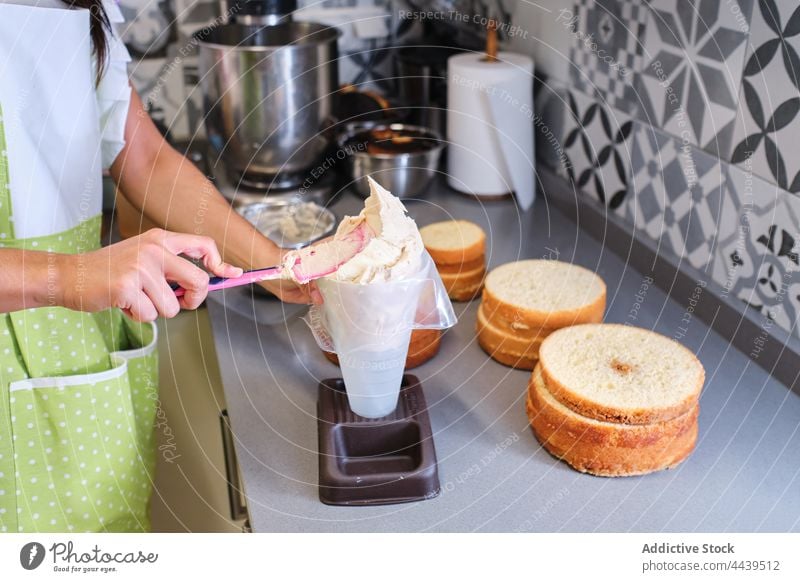 Cook putting cream into pastry bag while preparing cake in kitchen woman cook dessert apron food female sweet prepare delicious homemade confectionery culinary