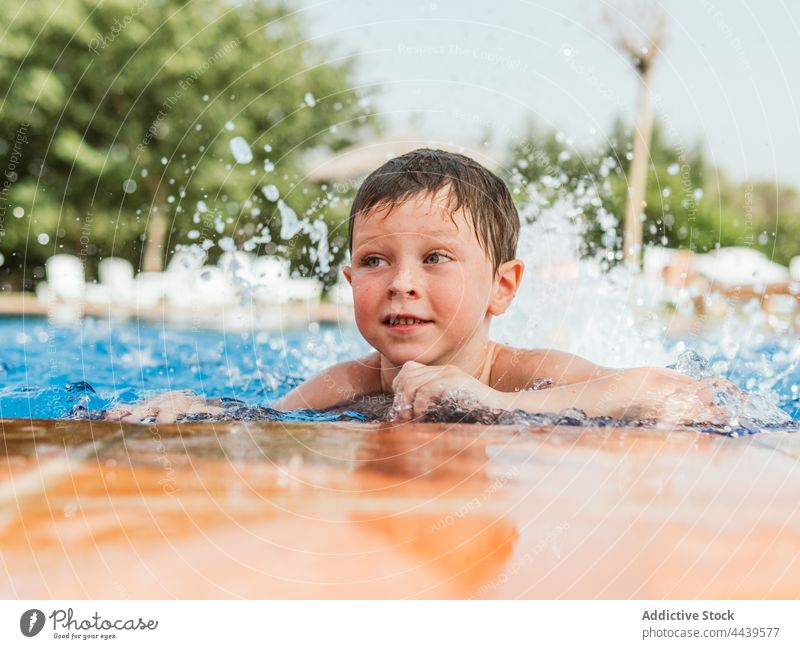 Cheerful boy in swimming pool in summer child poolside cheerful having fun water wet hair kid joy smile weekend happy enjoy pleasure vacation optimist charming