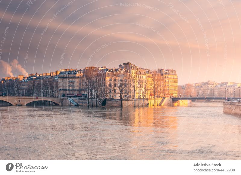 Old architecture on coast of river under bright sky district cityscape shore winter bridge historic old building dwell river bank tree embankment residential