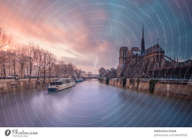 Motor ship on Seine river at sunset historic cathedral architecture landmark medieval sightseeing heritage catholic culture sundown religion facade city water