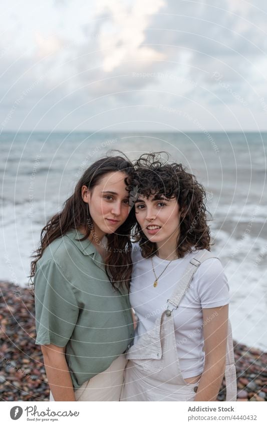 Homosexual couple of women embracing on sea shore embrace lesbian relationship love soulmate romantic seashore cloudy portrait sky girlfriend ocean together