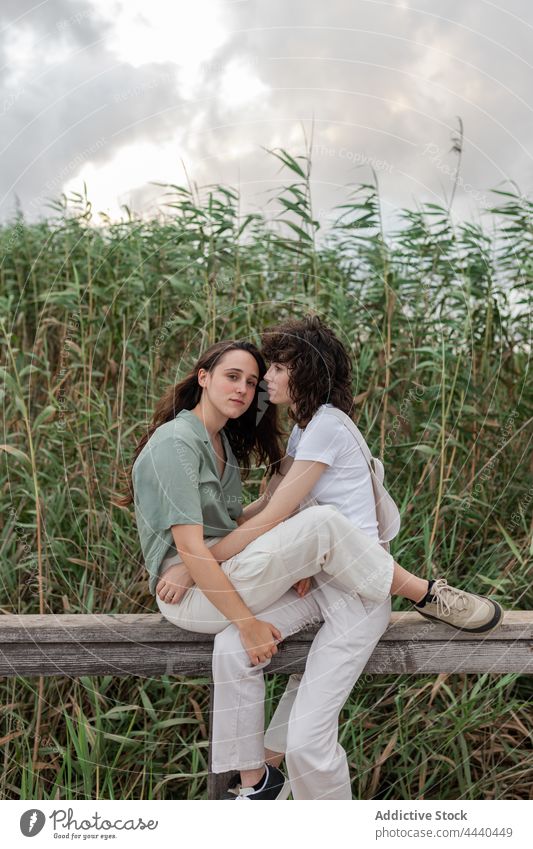 Lesbian couple interacting on fence against plants girlfriend same sex relationship love romantic spend time weekend countryside women lesbian embrace natural